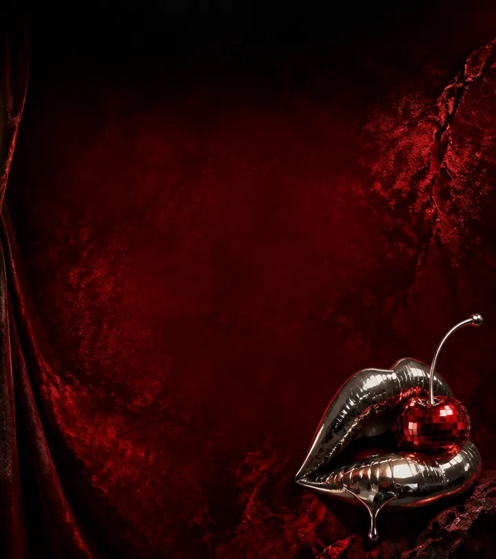Chrome lips holding a disco-ball cherry in front of a red velvet curtain